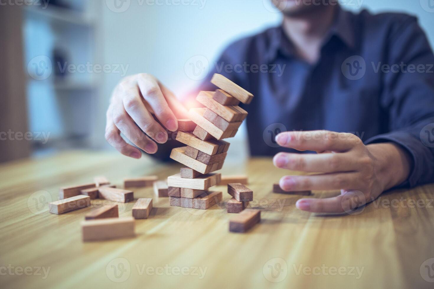 Business strategy concept with hands playing a wooden block tower game, symbolizing risk and stability. Planning risk management photo