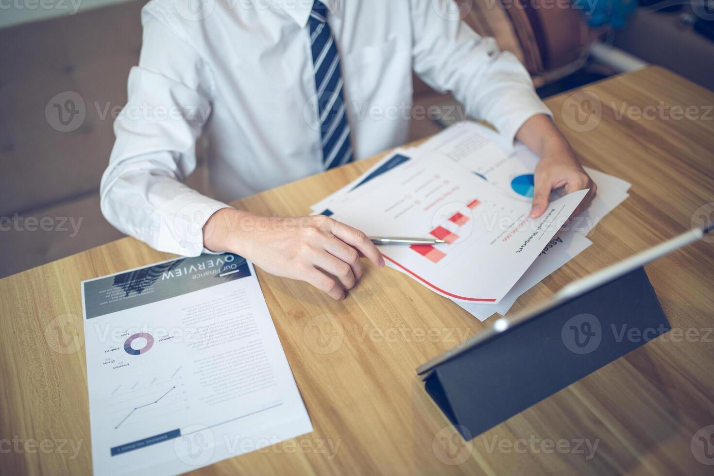 Businessman analyzing bar graph data with pen in hand, laptop and coffee on desk. Business concept photo