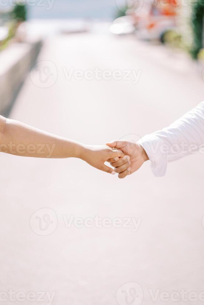 Man holds woman hand while standing on the road. Cropped. Faceless photo