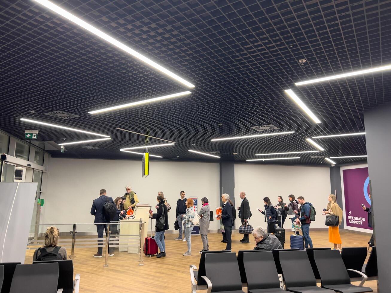 Belgrade, Serbia - 13 august 2023. Passengers with luggage stand in line at the check-in desk at the airport. Side view photo