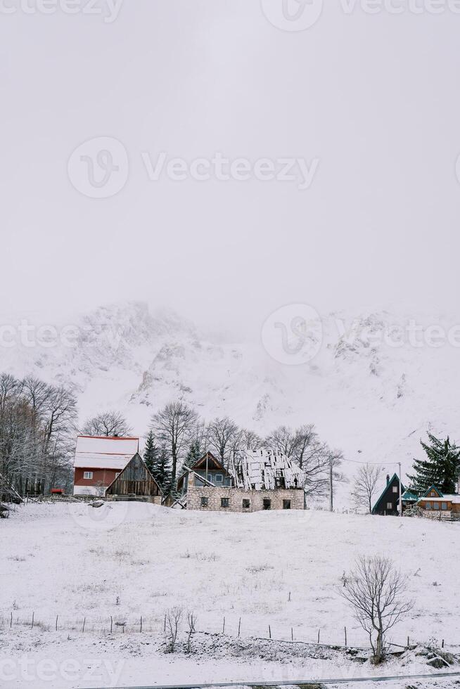 Snow-covered house under construction in a small village at the foot of the mountains photo