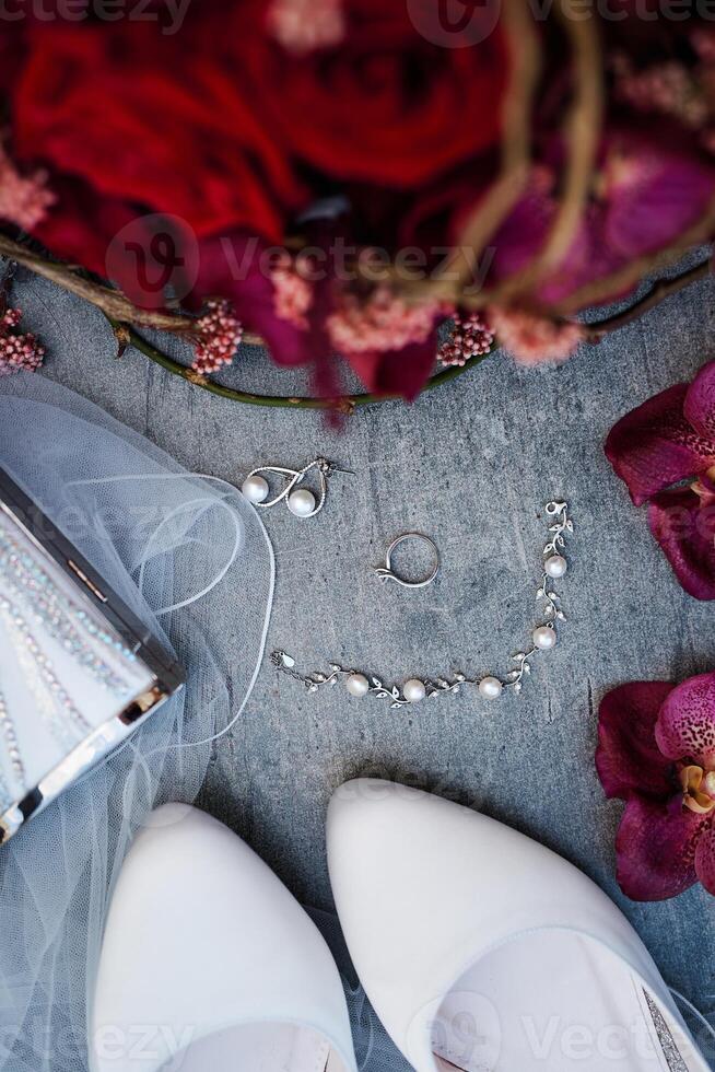 Pearl earrings and a bracelet lie next to the wedding ring on the table. Top view photo