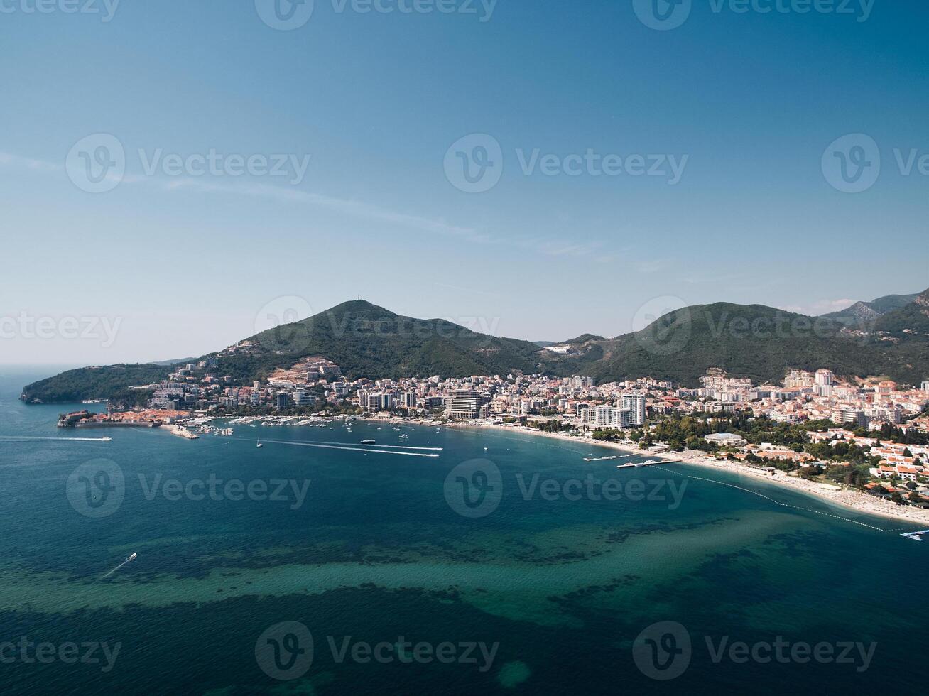 Motorboats sail along the Bay of Kotor opposite the resort coast of Budva. Montenegro. Drone photo