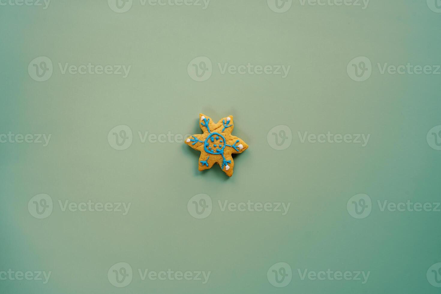 Glazed cookies in the shape of a snowflake lies on a green background photo