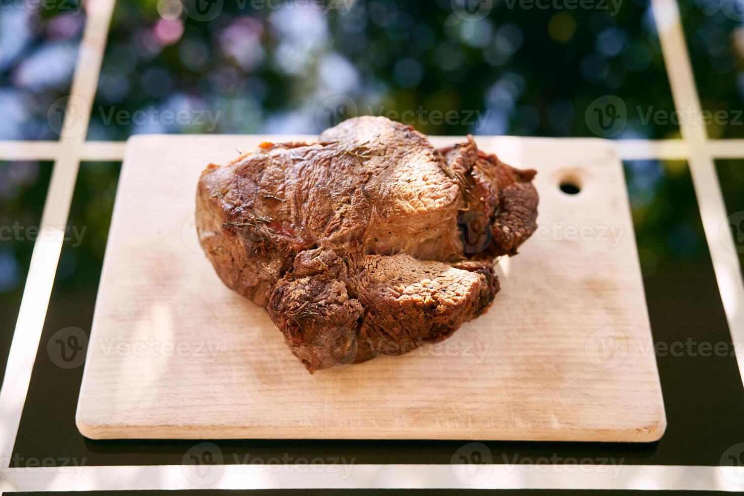 asado carne de vaca en un corte tablero mentiras en un vaso mesa en el luz de sol. parte superior ver foto