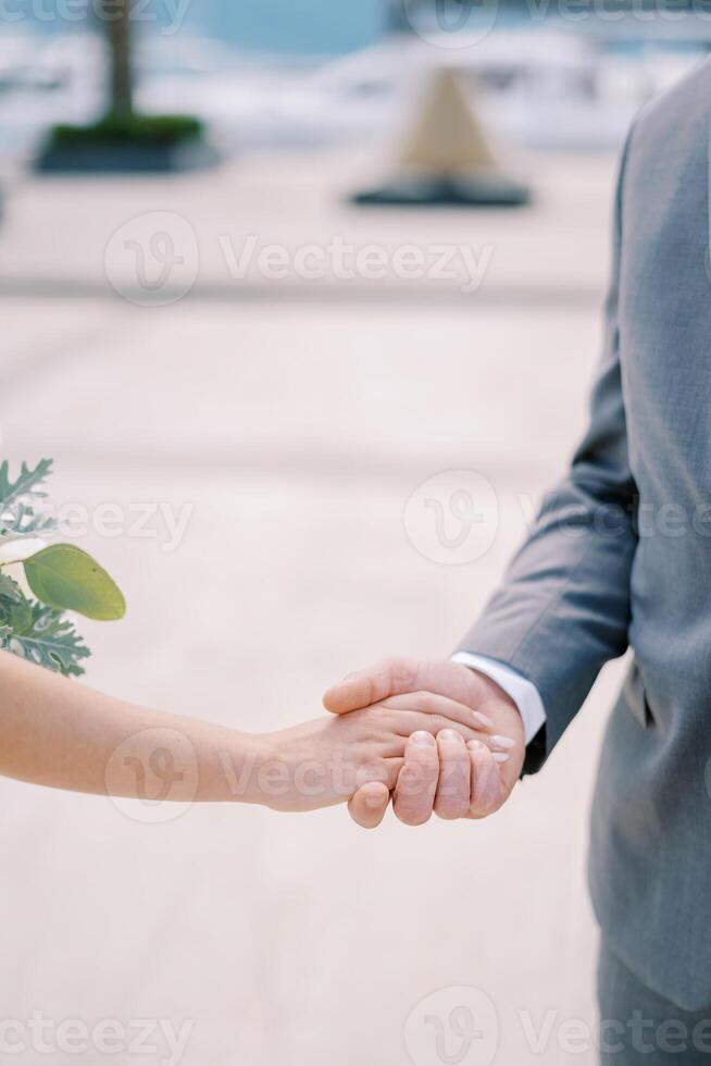 Groom holds bride hand with a bouquet. Cropped. Faceless photo