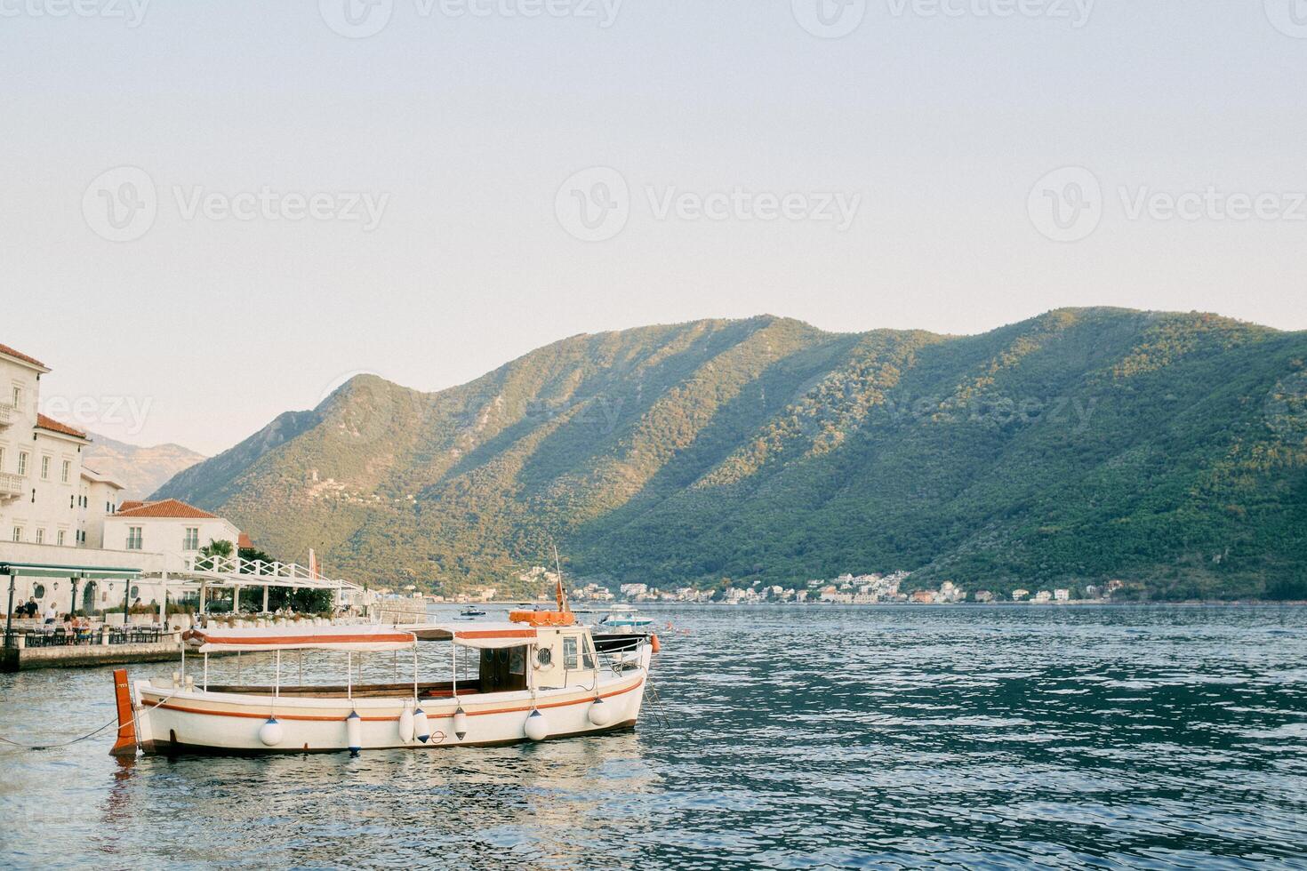 Tour boat is moored near the promenade with covered open-air restaurants. Perast, Montenegro photo