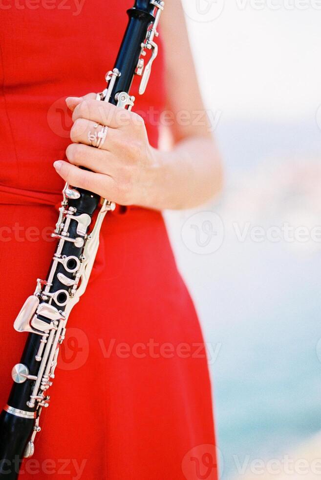 Girl-musician stands with a flute in her hands. Cropped. Faceless photo