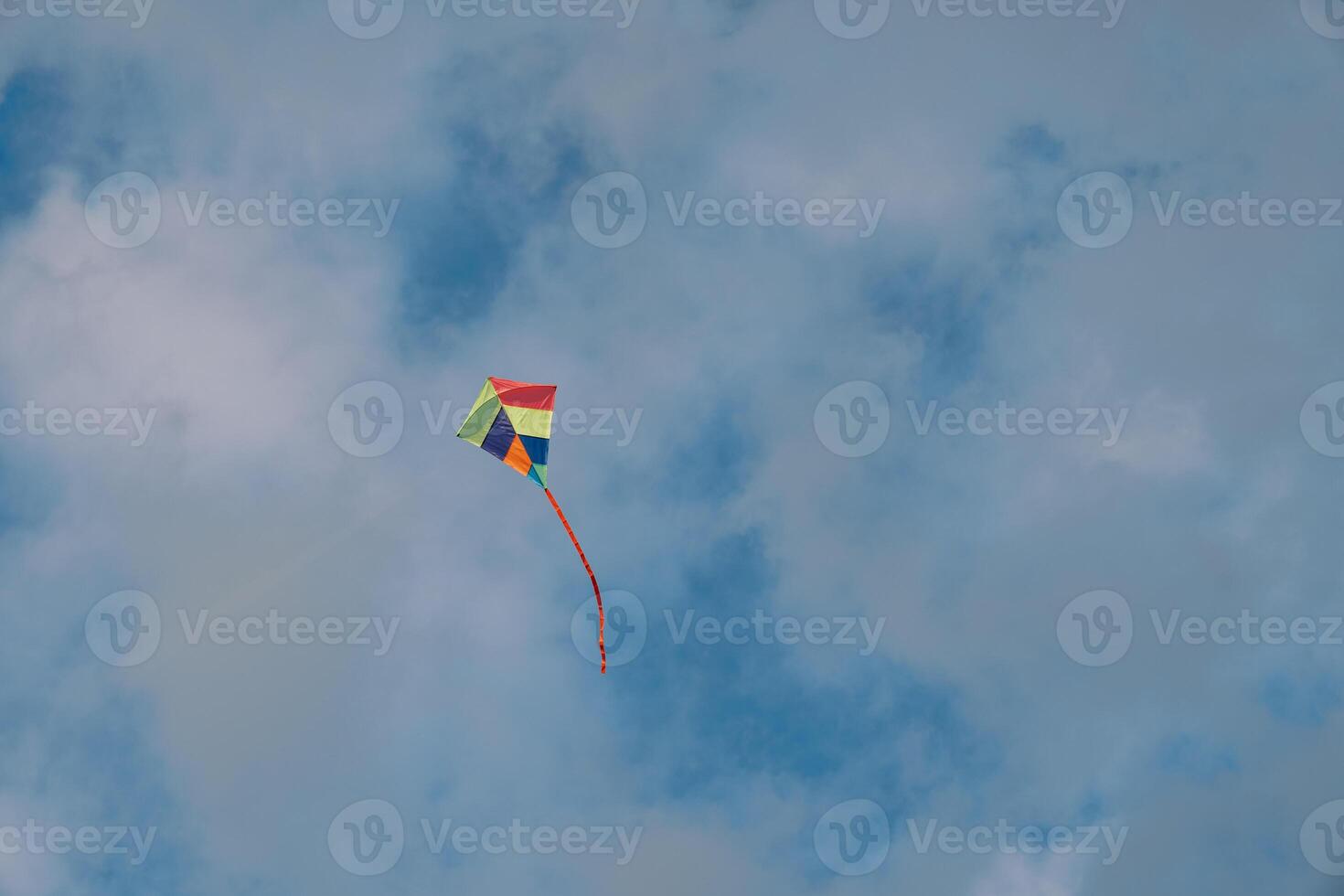 Colorful kite soars in the cloudy sky photo