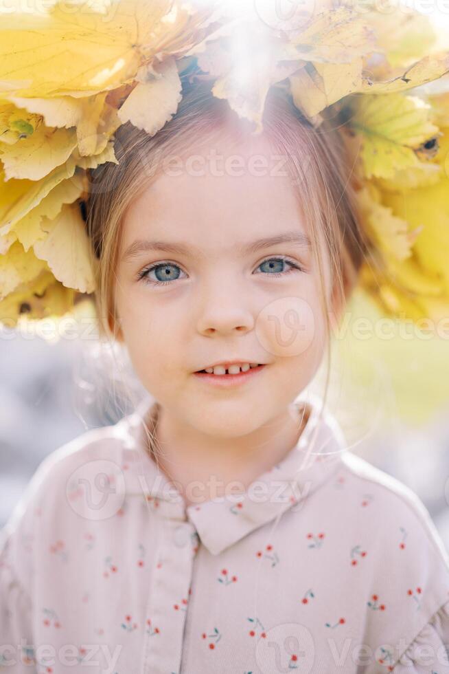 pequeño sorprendido niña vistiendo un corona de amarillo hojas. retrato foto