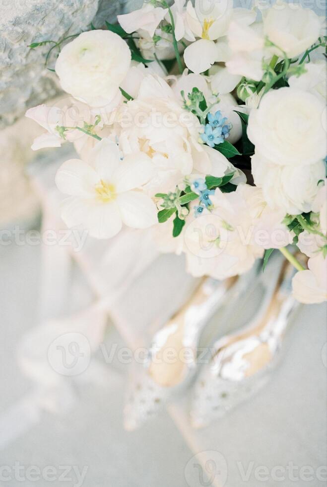 Wedding bouquet stands on the table near bride shoes. Top view photo