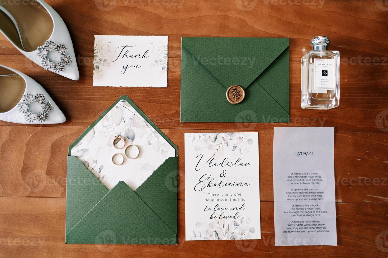 Bride shoes stand on a wooden table next to a bottle of perfume and invitations in envelopes photo