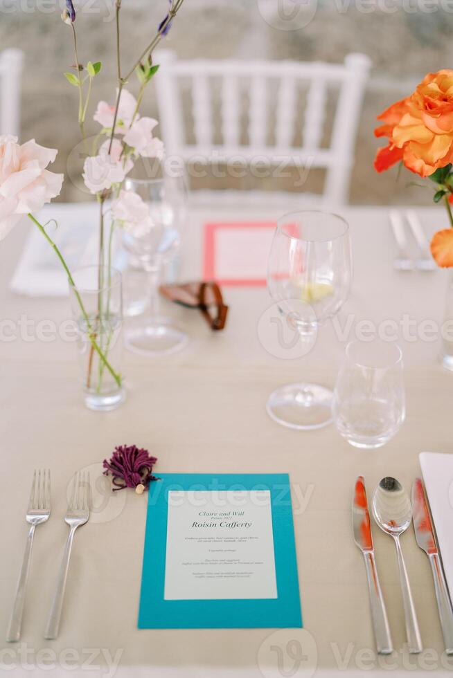 Bright personalized invitation lies on the festive table next to a bouquet of flowers photo