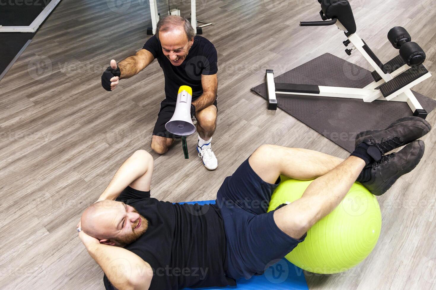 senior trainer screaming with a megaphone at the young athlete photo