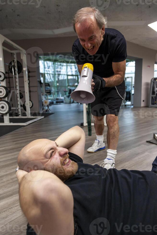 senior trainer screaming with a megaphone at the young athlete photo