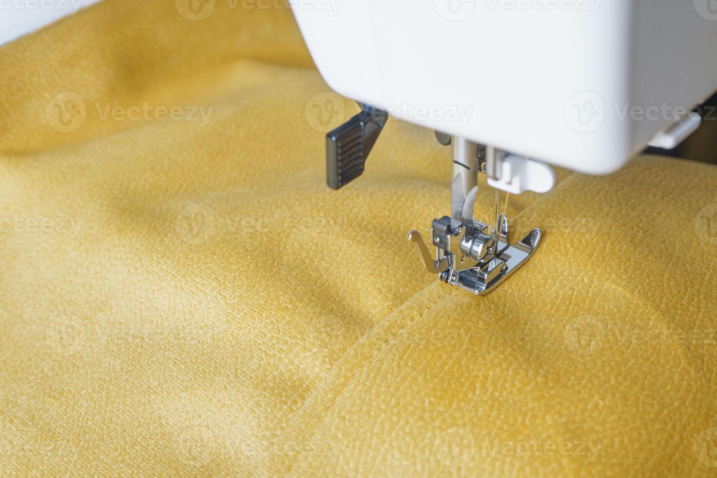 Modern sewing machine with yellow velours fabric close up photo