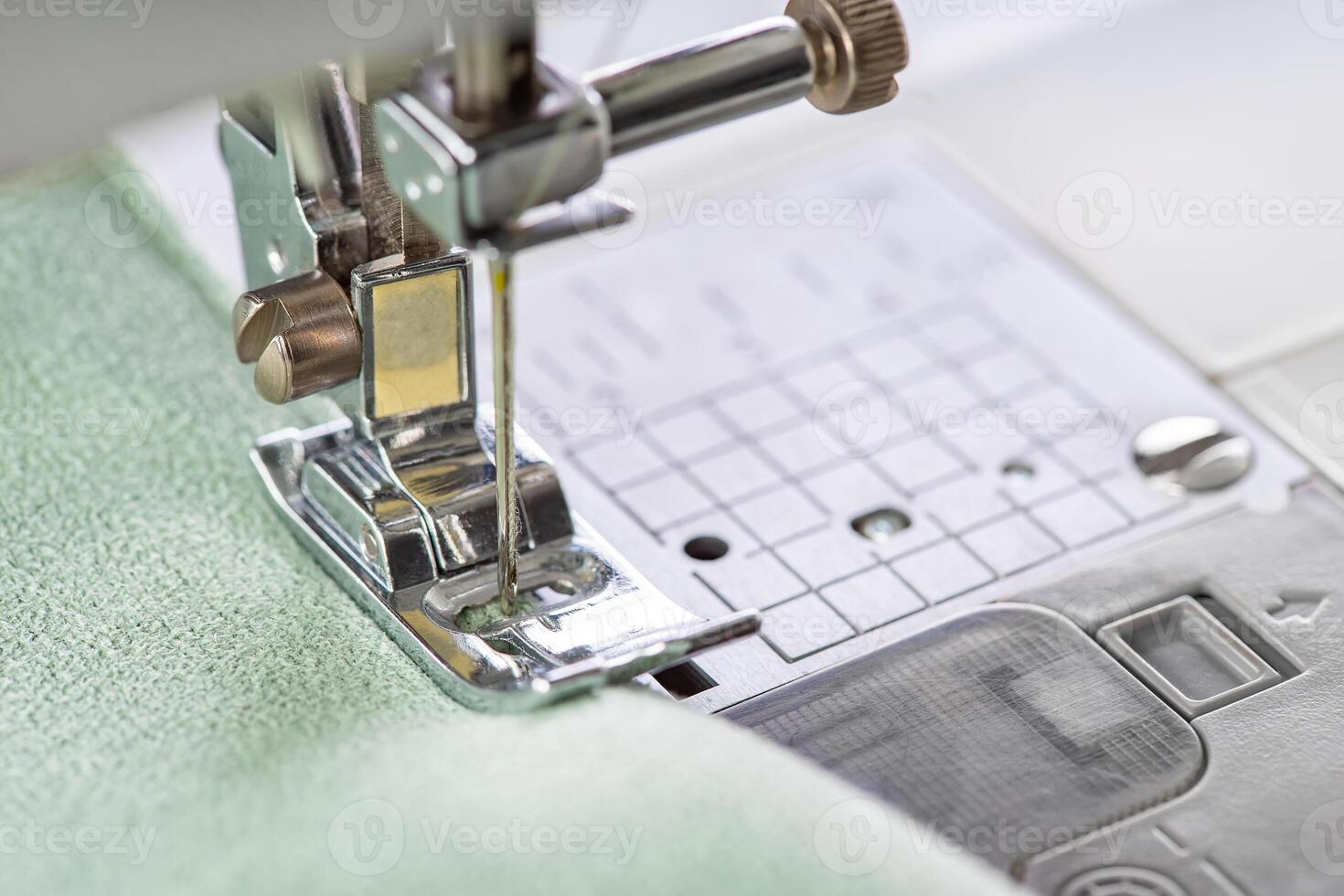 Modern sewing machine presser foot with green fabric and thread, closeup, macro photo