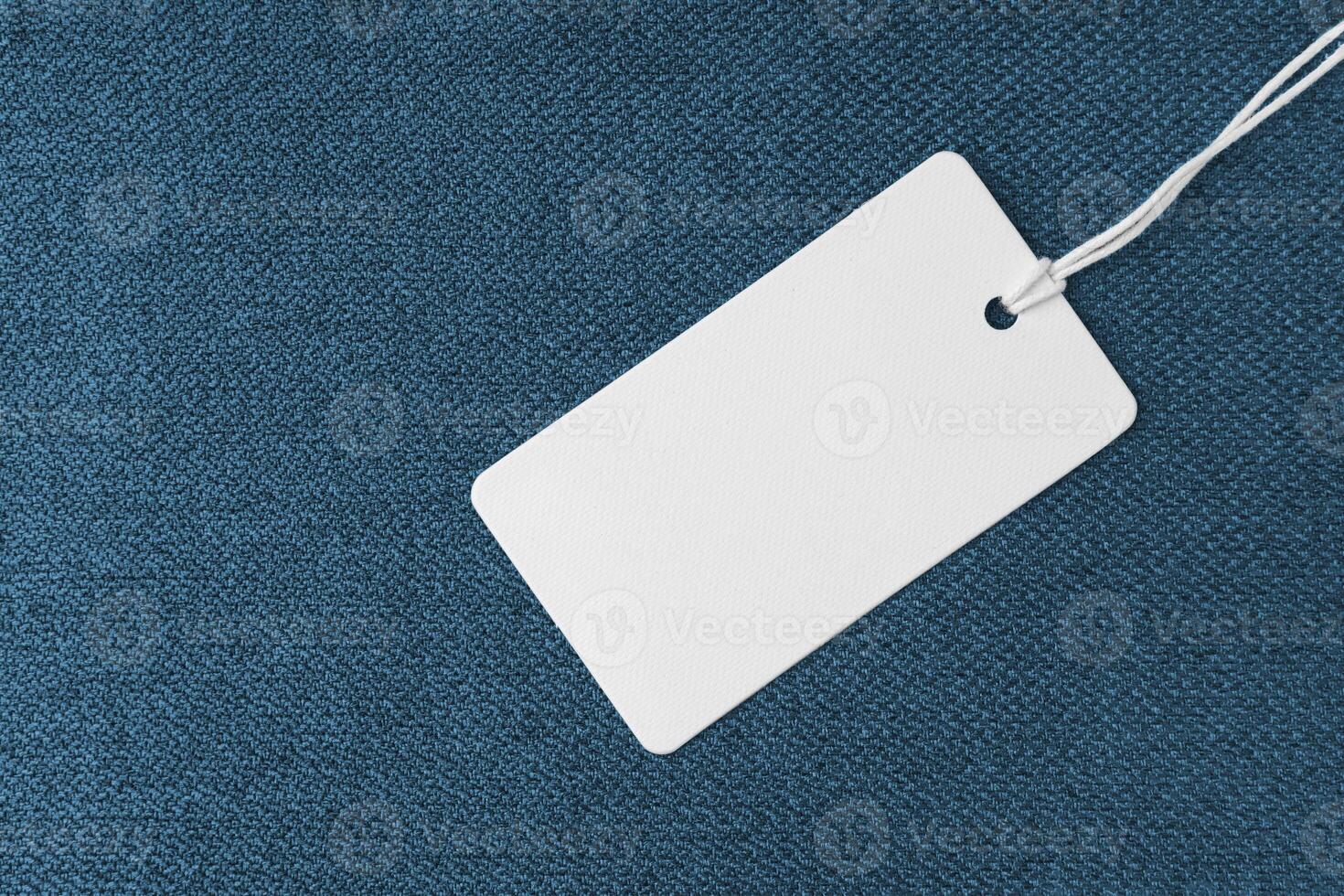 Textile background, blue coarse fabric texture with white empty clothing tag photo