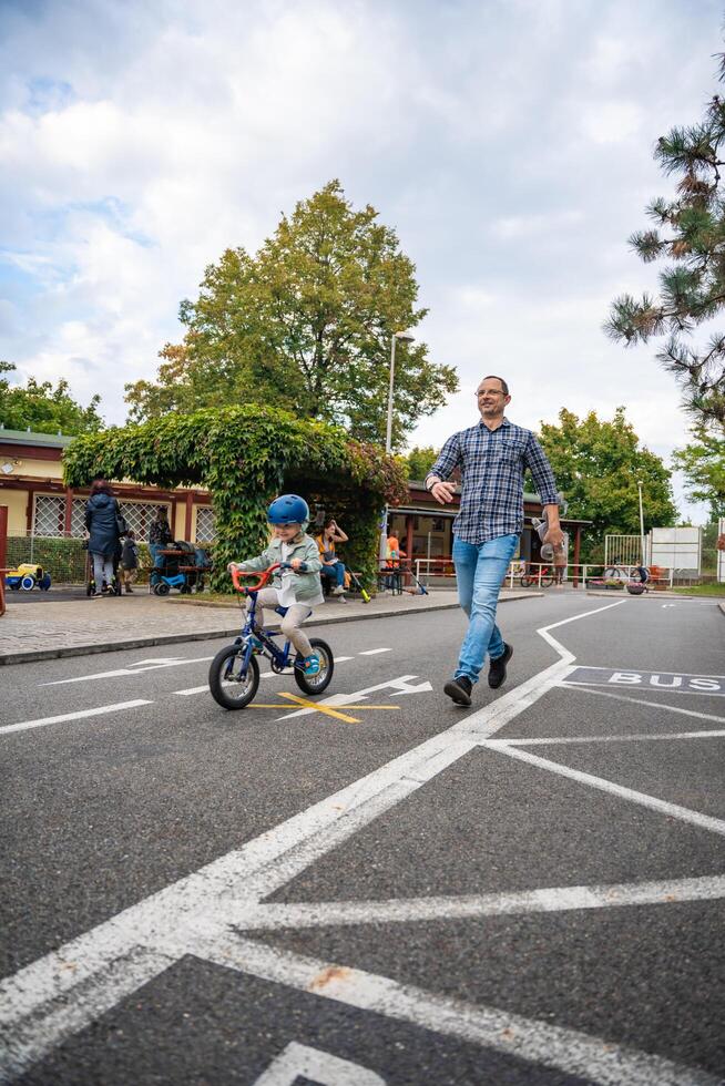 Prague, Czech republic - October 10, 2023. Young happy father teaches child daughter to ride public bike on traffic playground in Prague, Czech republic, Europe. High quality photo