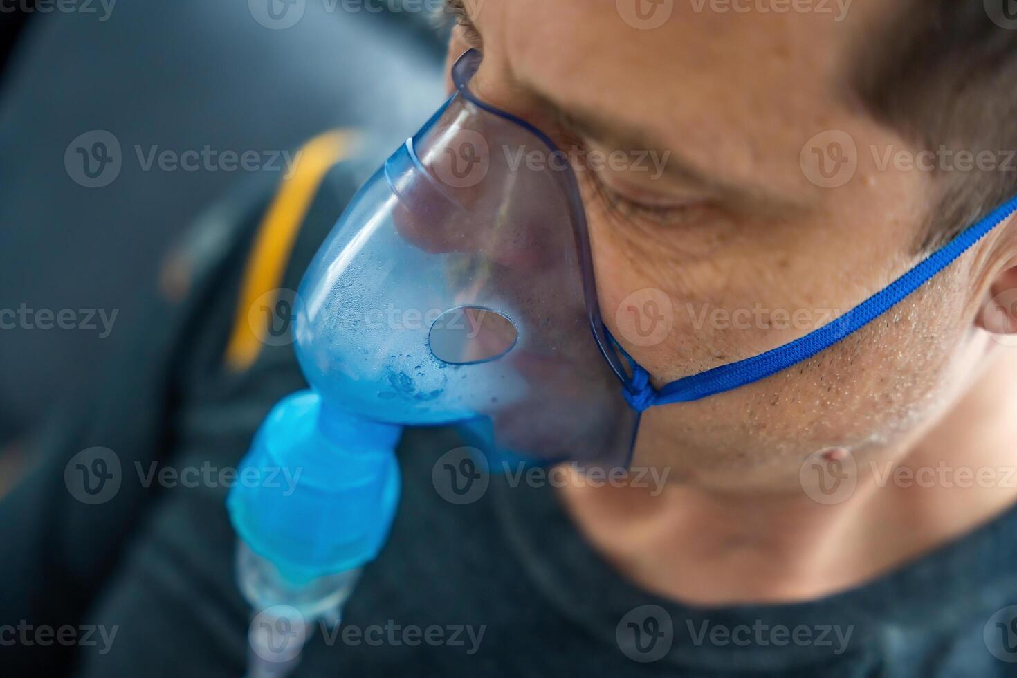 Close up view of unhealthy man wearing nebulizer mask in home. Health, medical equipment and people concept. High quality photo