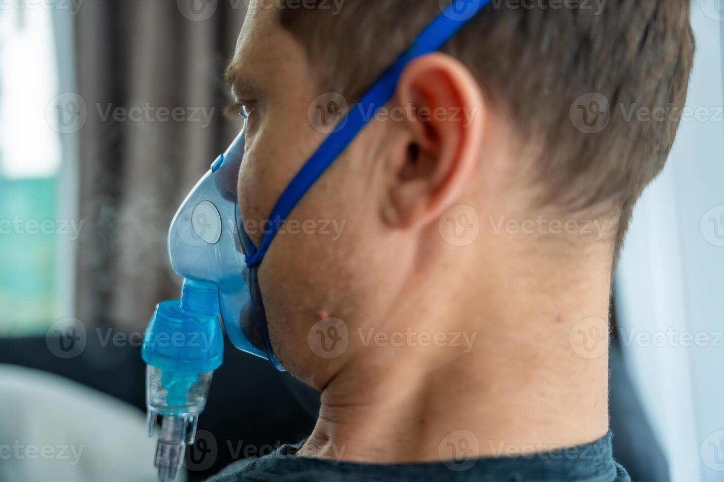 Unhealthy man wearing nebulizer mask in home. Health, medical equipment and people concept. High quality photo