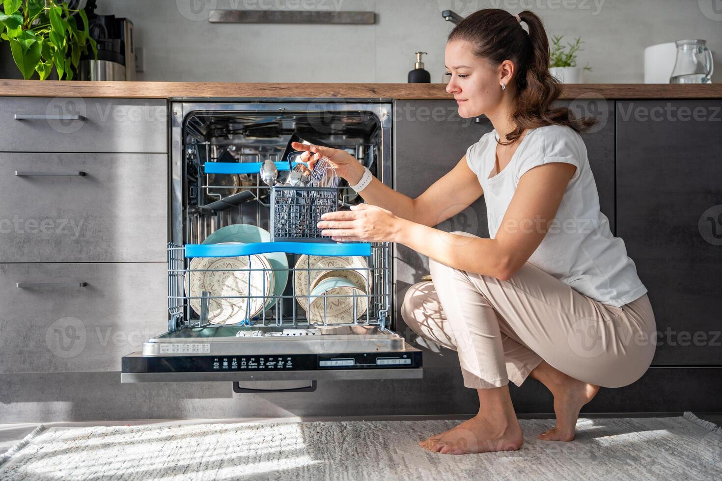 A woman removes clean ceramic dishes from dishwasher. Household and useful technology concept. High quality photo