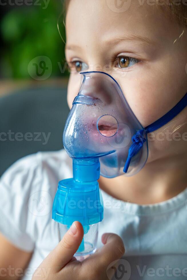 cerca arriba ver de pequeño niña son sentado y participación un nebulizador máscara propensión en contra el rostro, vías respiratorias tratamiento concepto. alto calidad foto