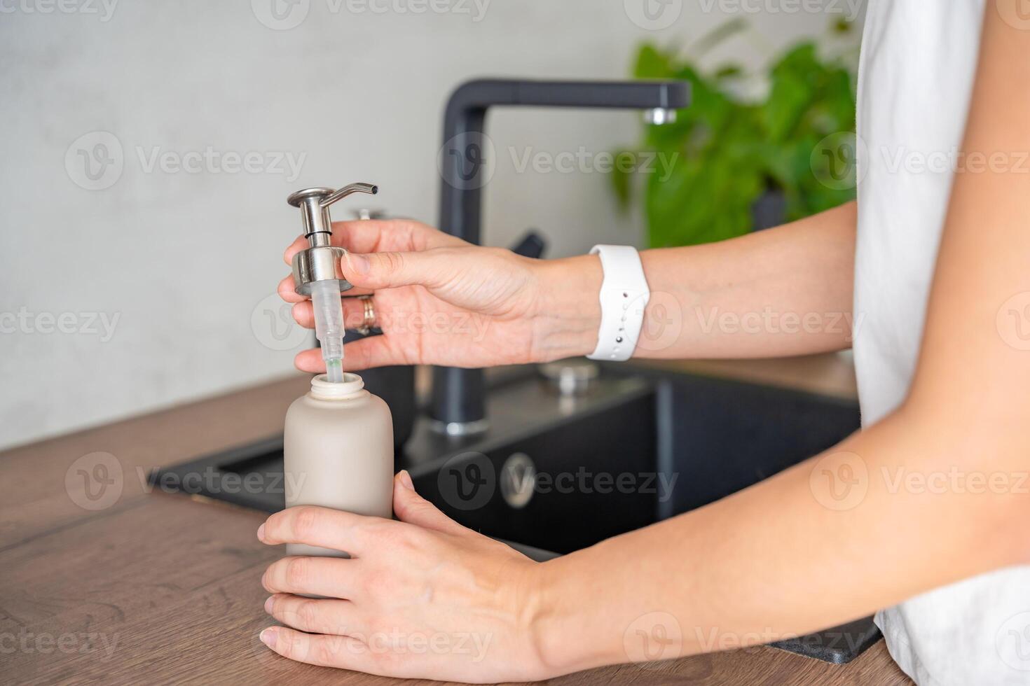 A woman uses soap or detergent in a reusable bottle. Eco-friendly lifestyle. High quality photo