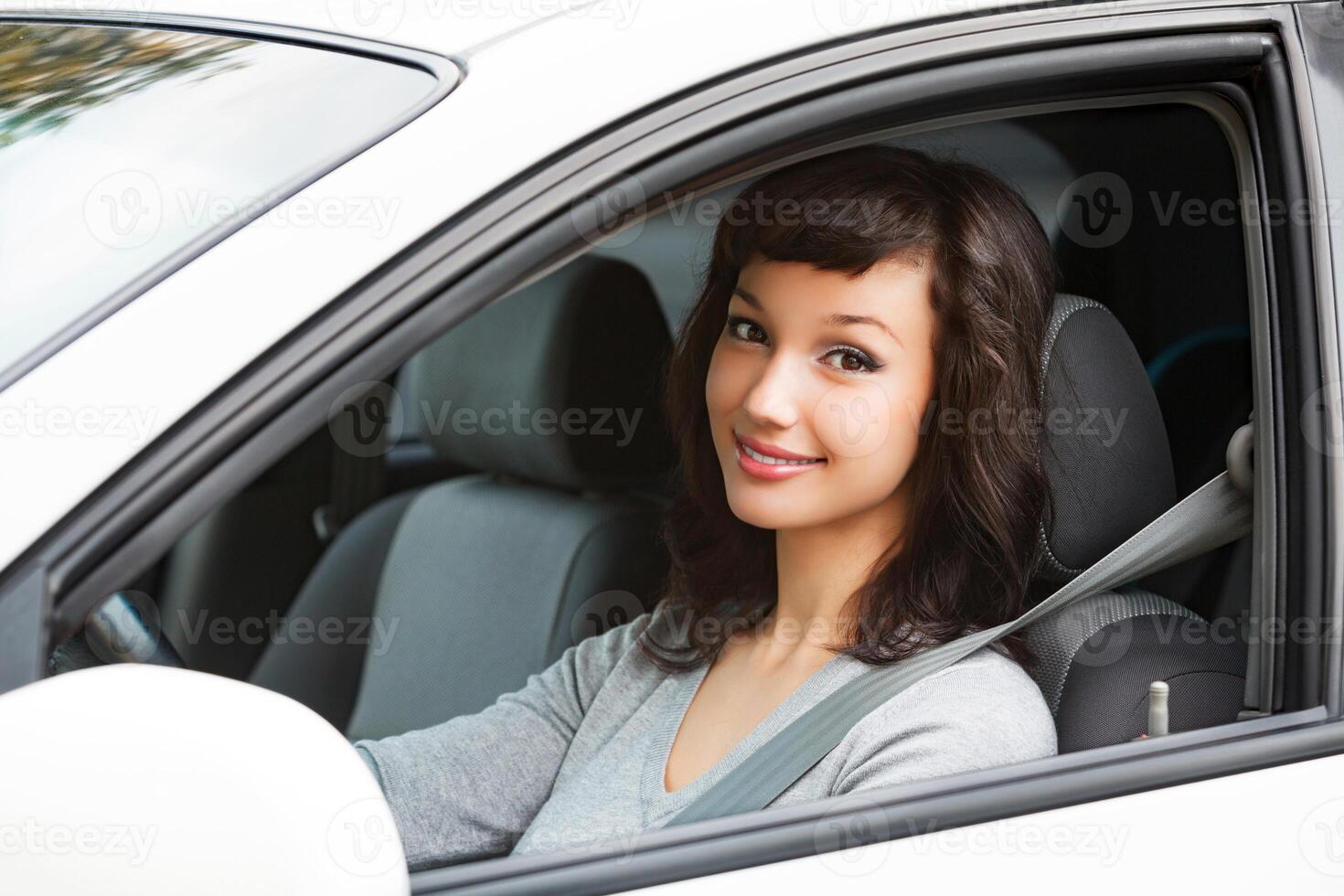 bonito mujer conductor sonriente a usted desde el blanco coche foto