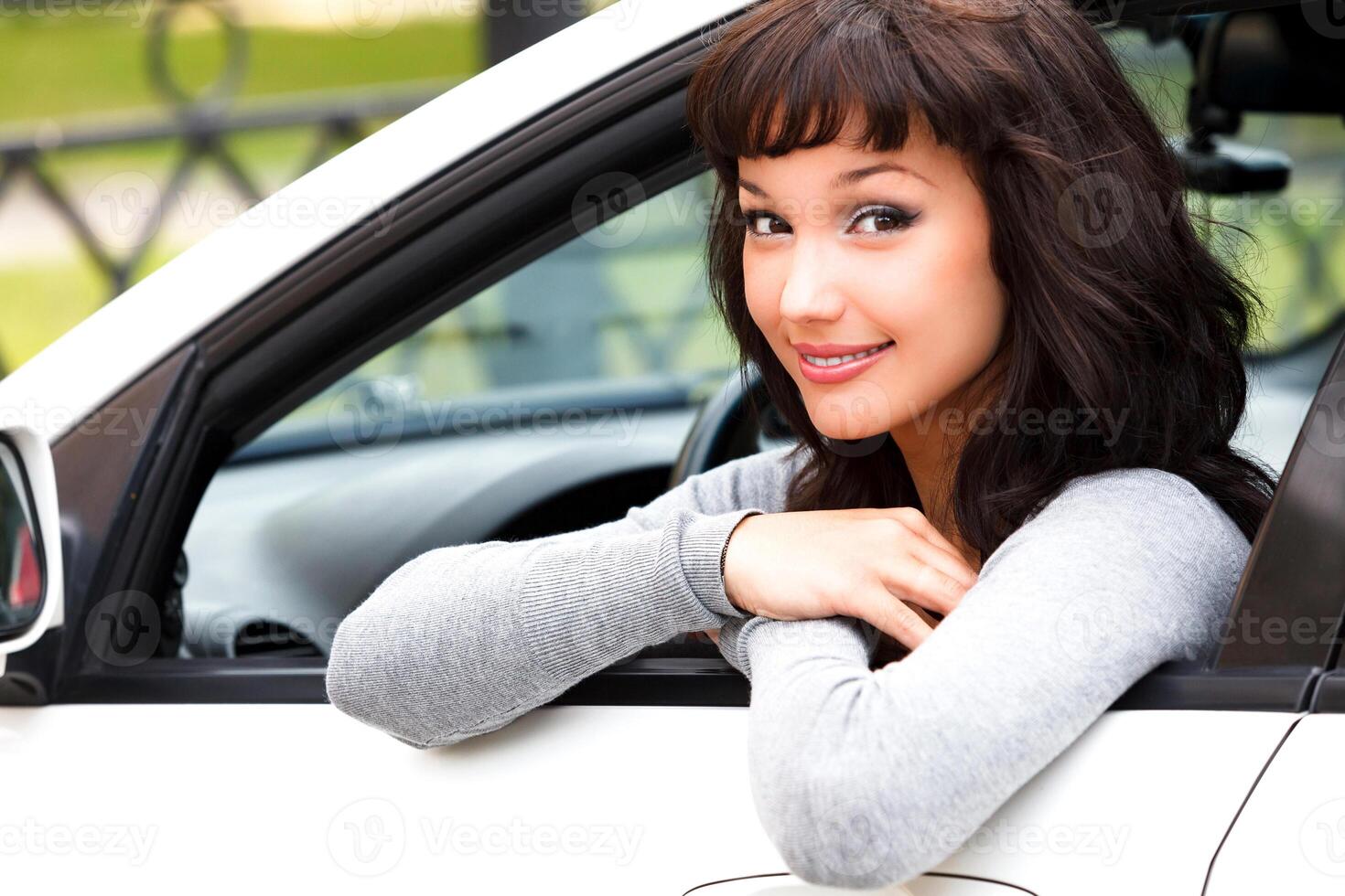contento propietario de un nuevo coche. joven bonito mujer conductor sonriente a usted foto