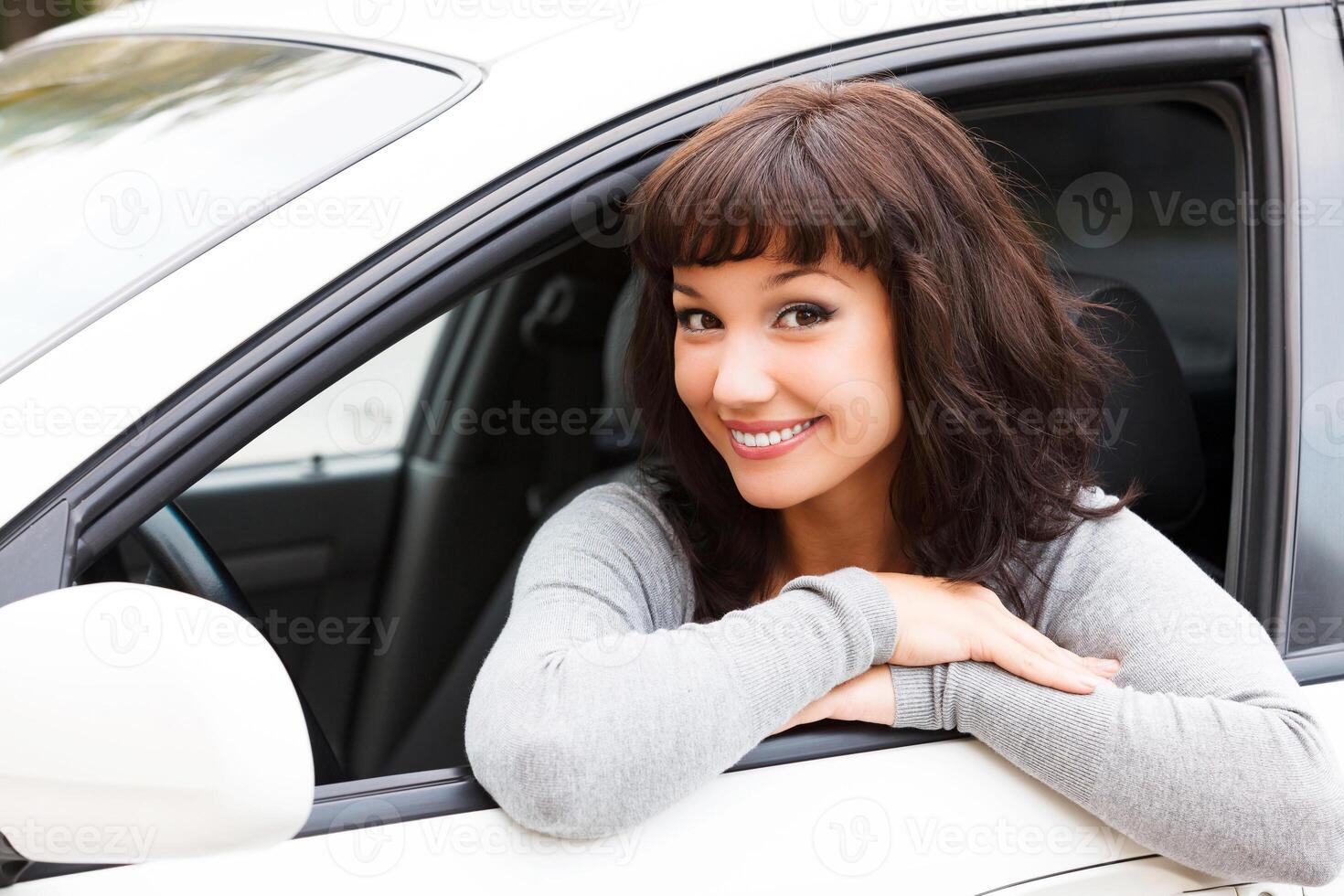 contento propietario de un nuevo coche. joven bonito mujer conductor sonriente a usted foto