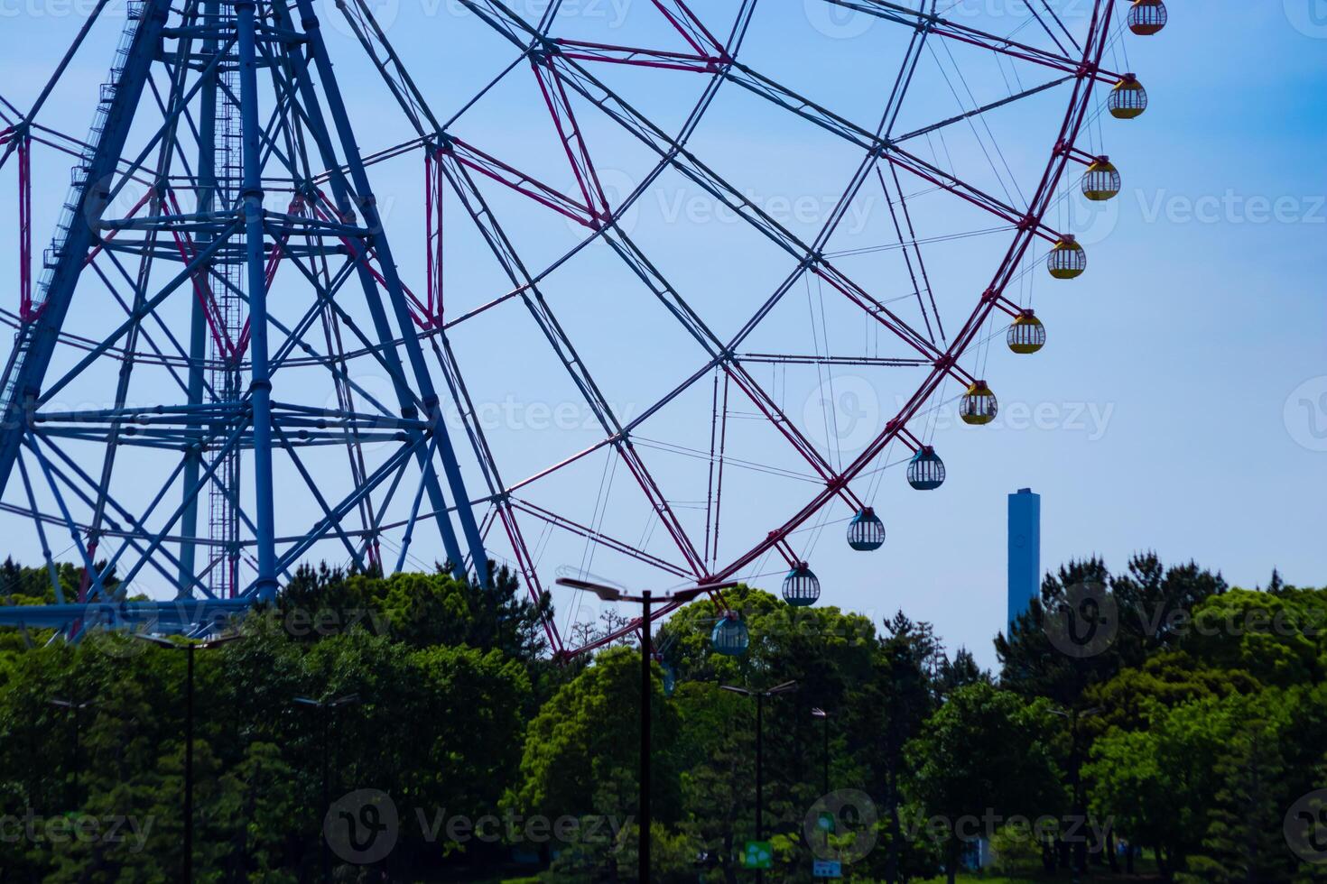 A ferris wheel at the park behind the blue sky telephoto shot photo