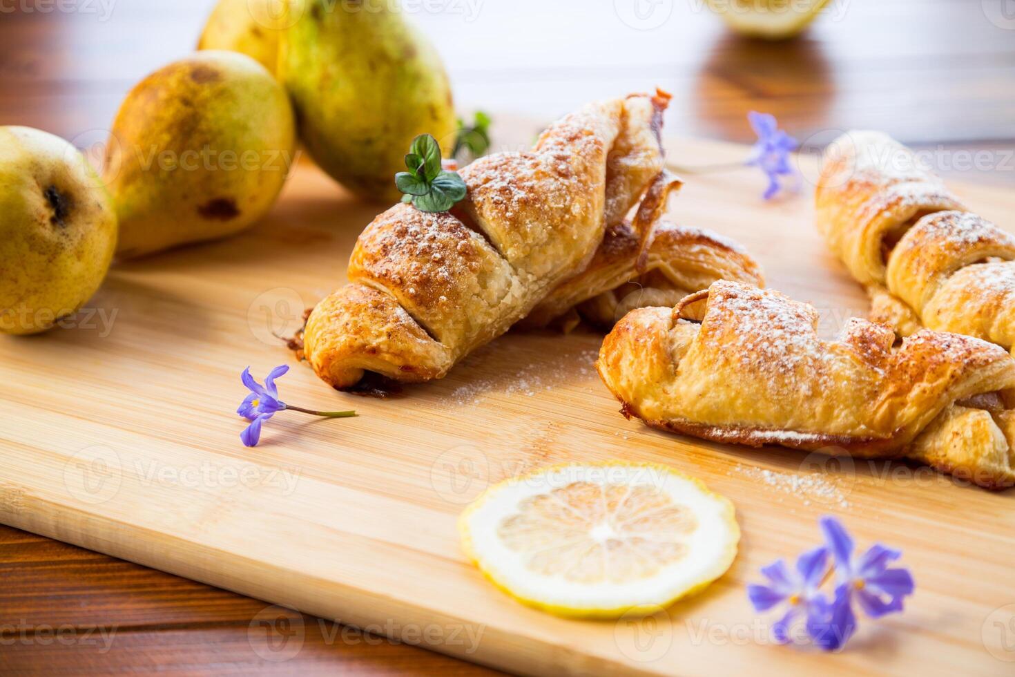 Sweet pastries, puff pastries with pears, on a wooden table photo