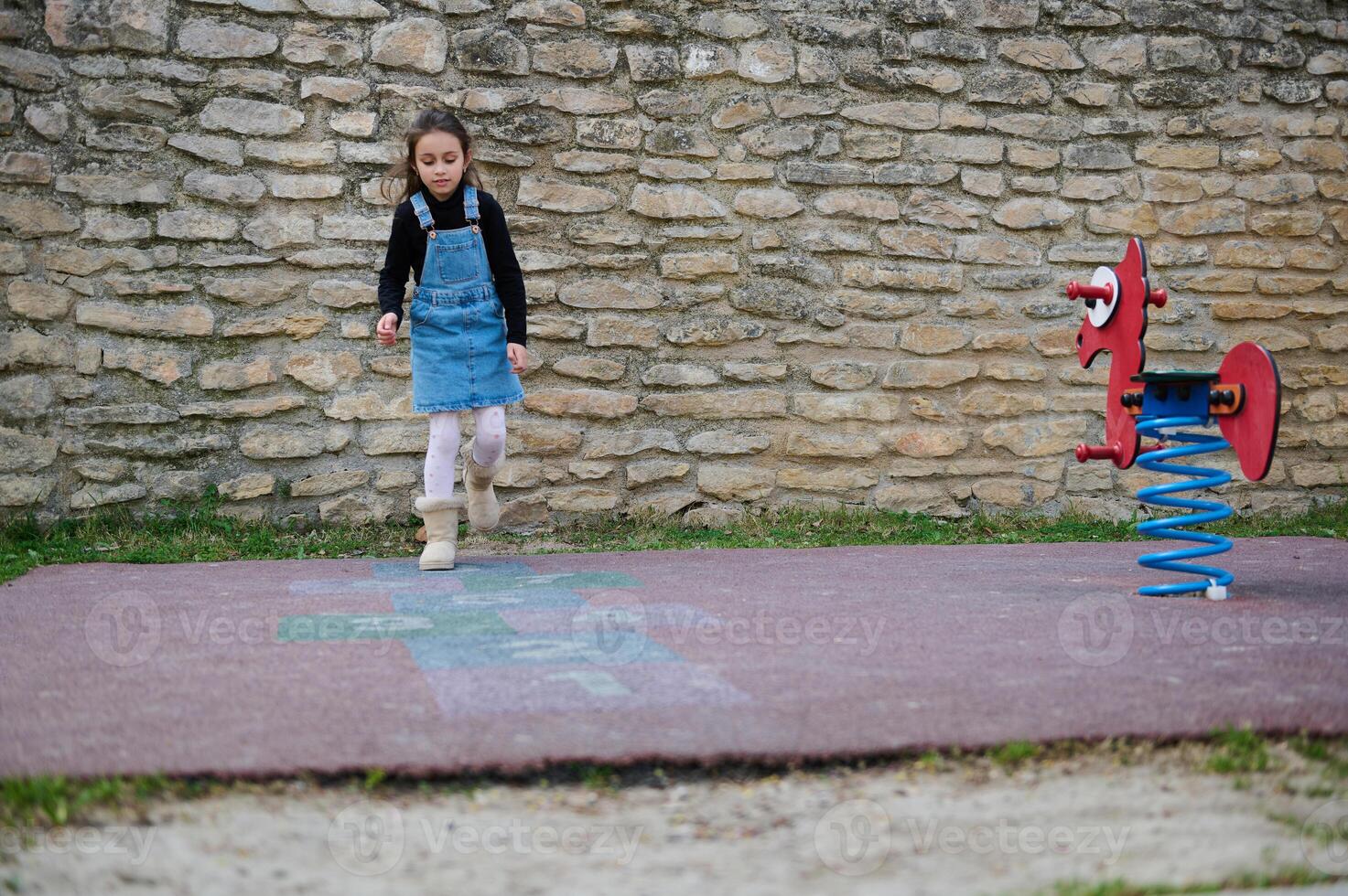 lleno longitud Disparo de un encantador pequeño niño niña jugando rayuela en el colegio patio de recreo foto