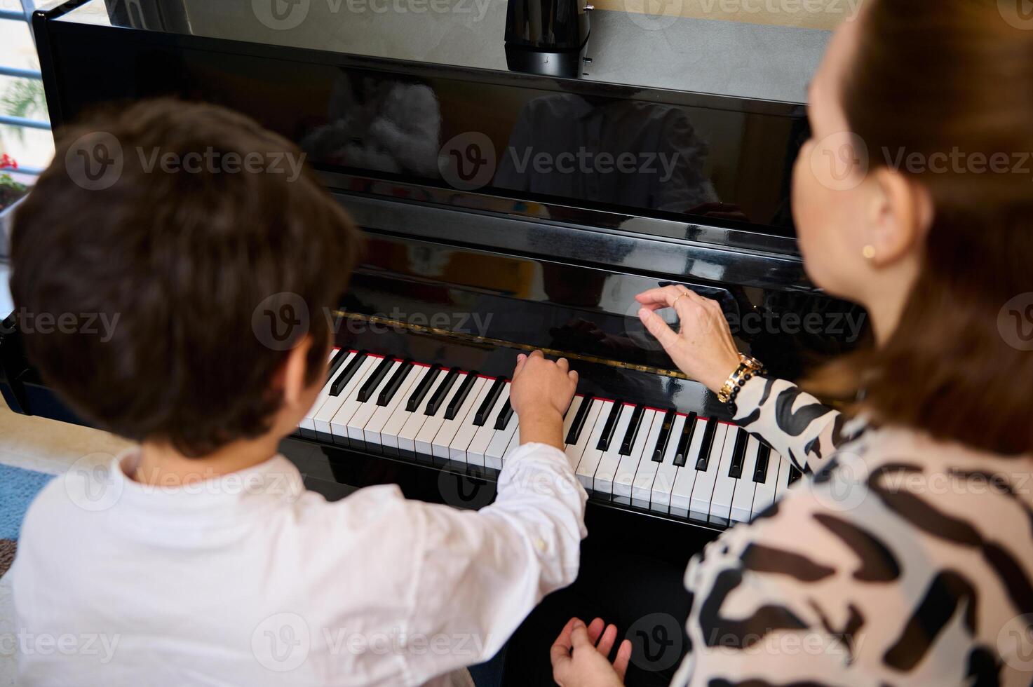 ver desde encima de un adorable adolescente chico disfrutando jugando grandioso piano a hogar, creando música y canción, ejecutando banda sonora en el pianoforte, composición un melodía durante música lección. foto