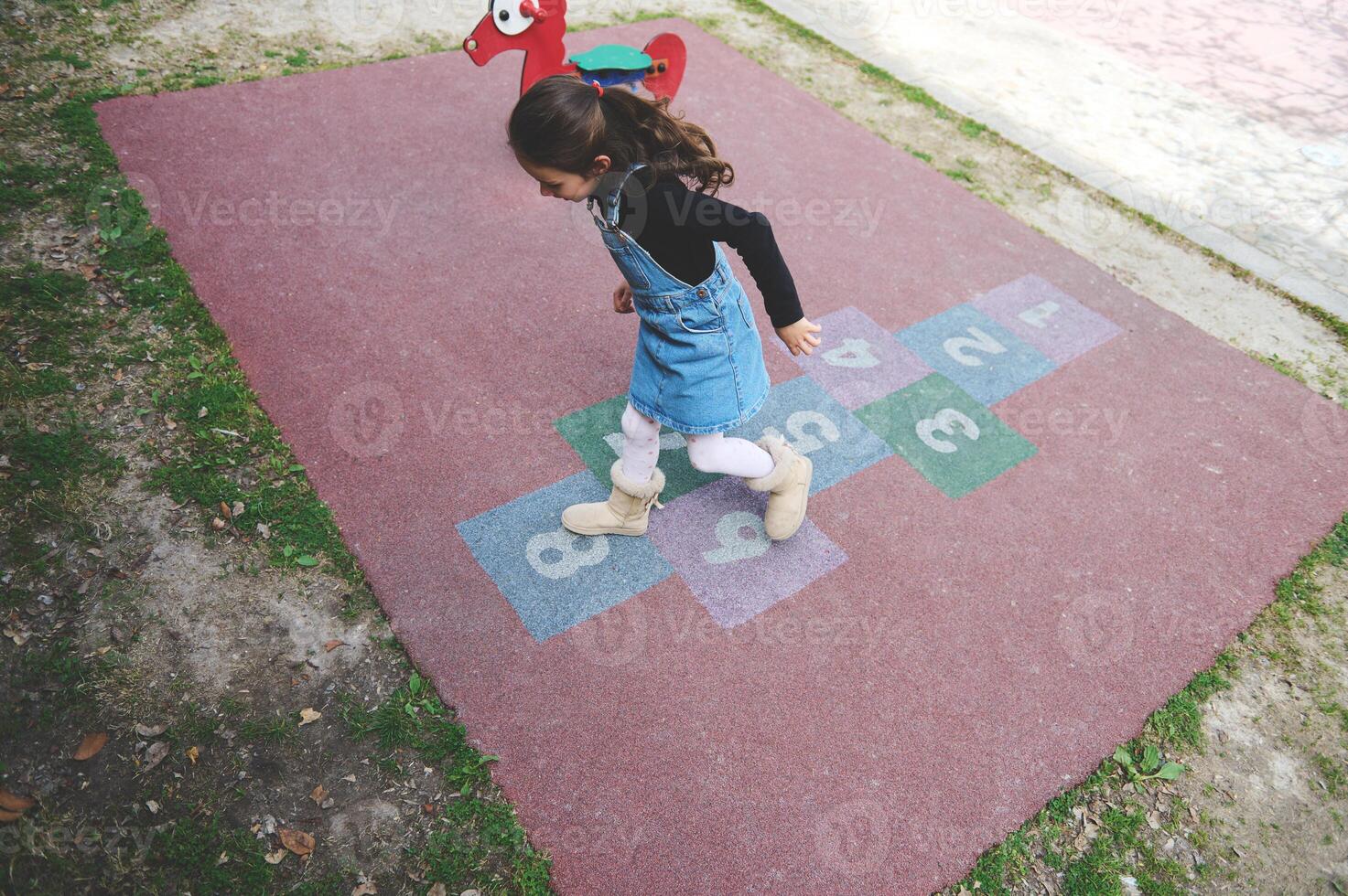 Overhead view child girl playing hopscotch on the school playground. Popular street children's games in classics photo