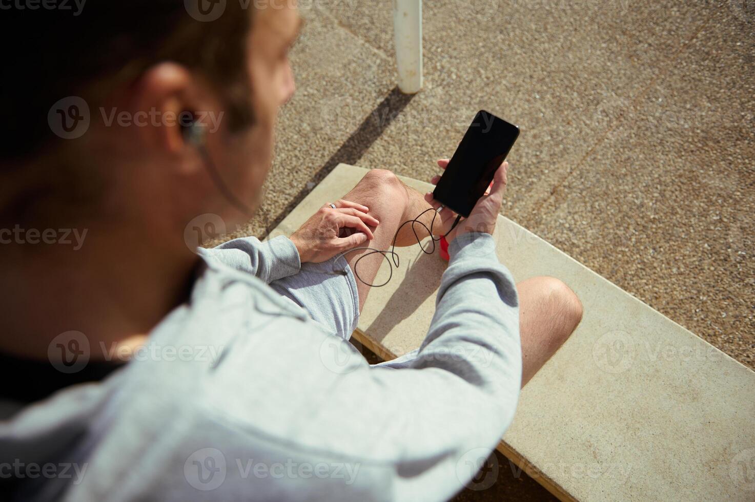 Overhead view of young athlete using mobile phone with blank black mockup screen, copy advertising space for mobile app photo
