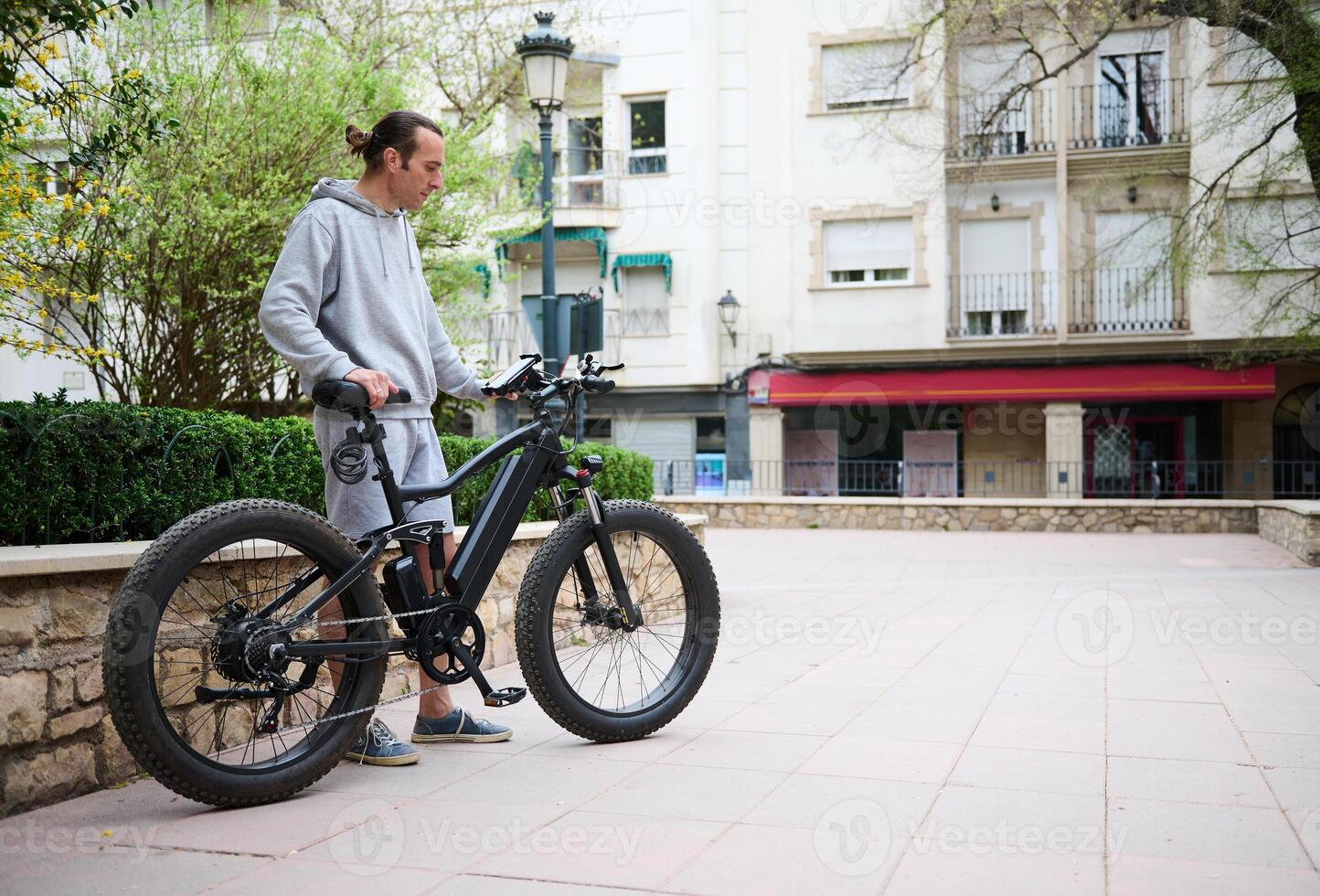 Young man in sports wear, renting and riding e-bikes in the city. Bike sharing city service photo