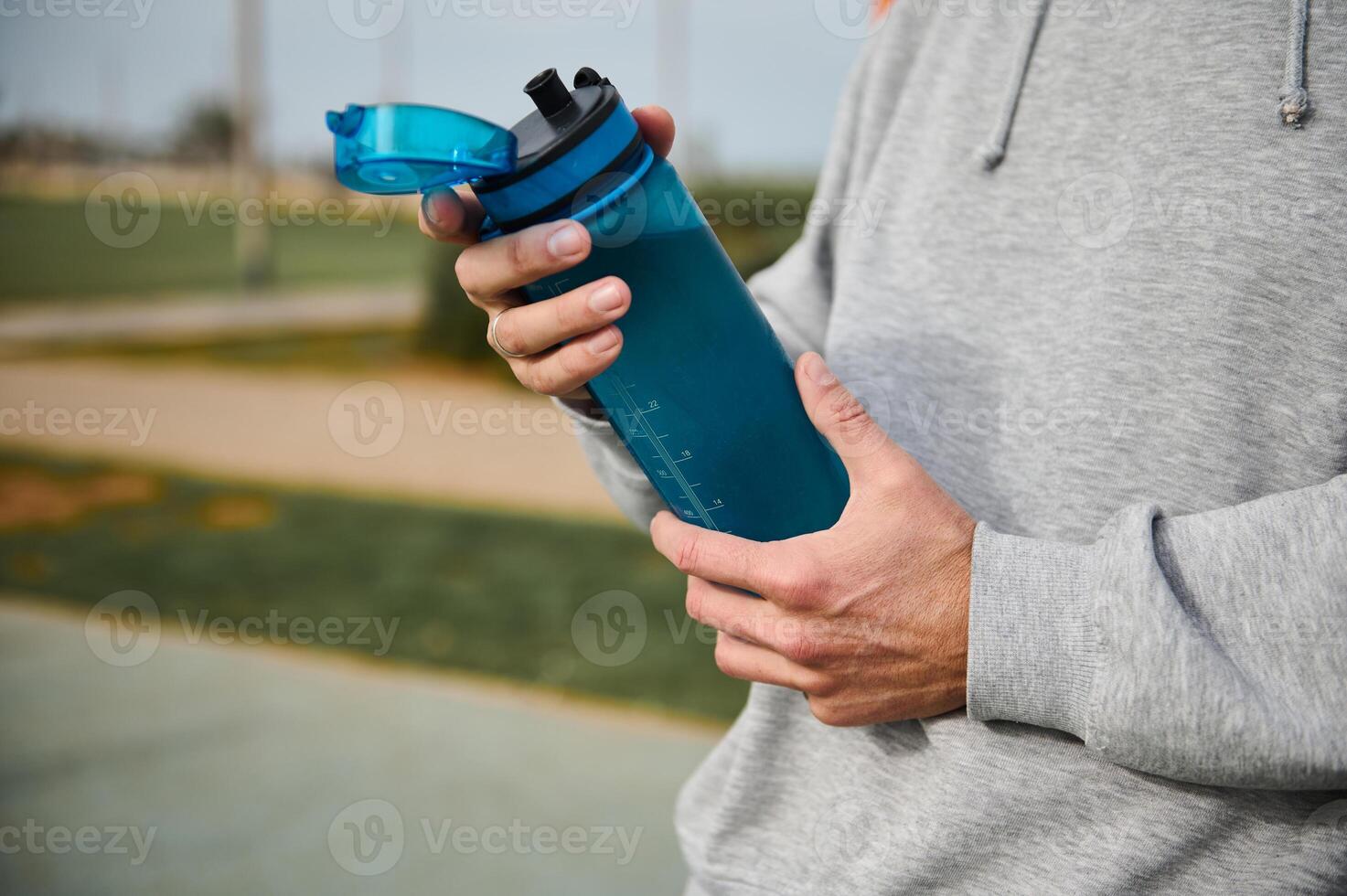 selectivo atención en el agua botella en el manos de un activo masculino atleta descansando después rutina de ejercicio o corriendo al aire libre foto