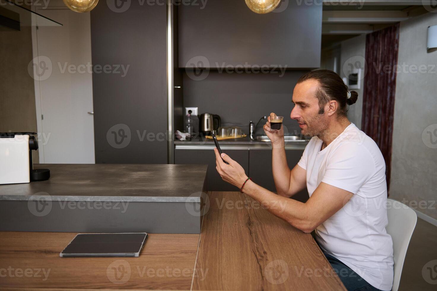 Side view relaxed young business man freelancer taking his morning coffee, reading news, checking social media content photo