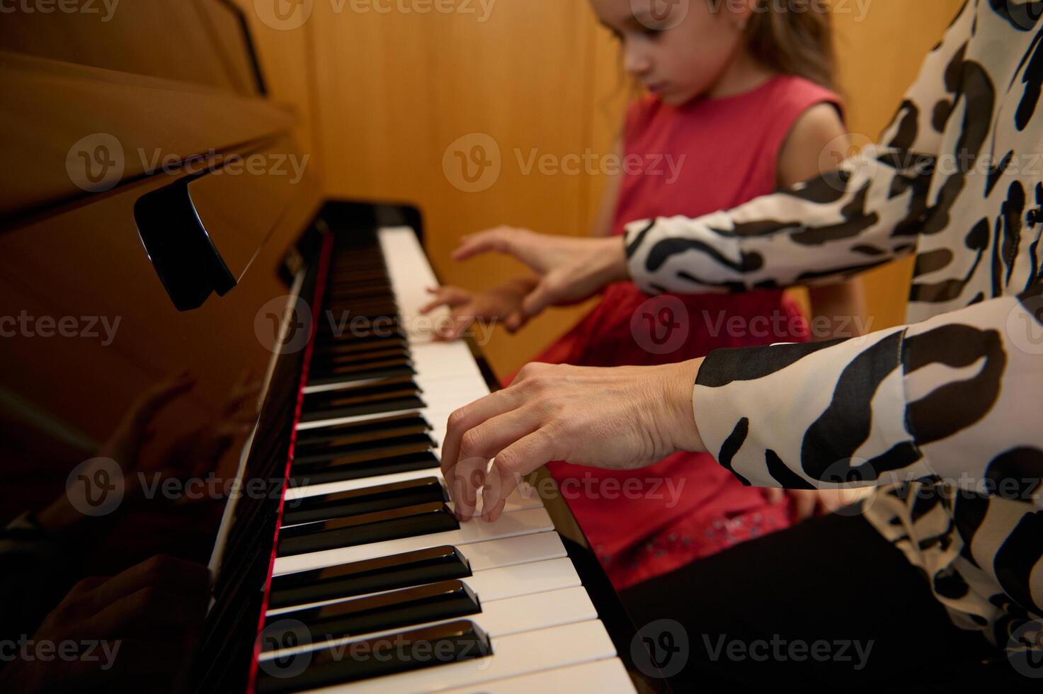 de cerca mujer pianista participación manos en piano teclado, conmovedor negro y blanco llaves, preformado clásico melodía durante mientras dando un música lección a su pequeño estudiante muchacha. foto