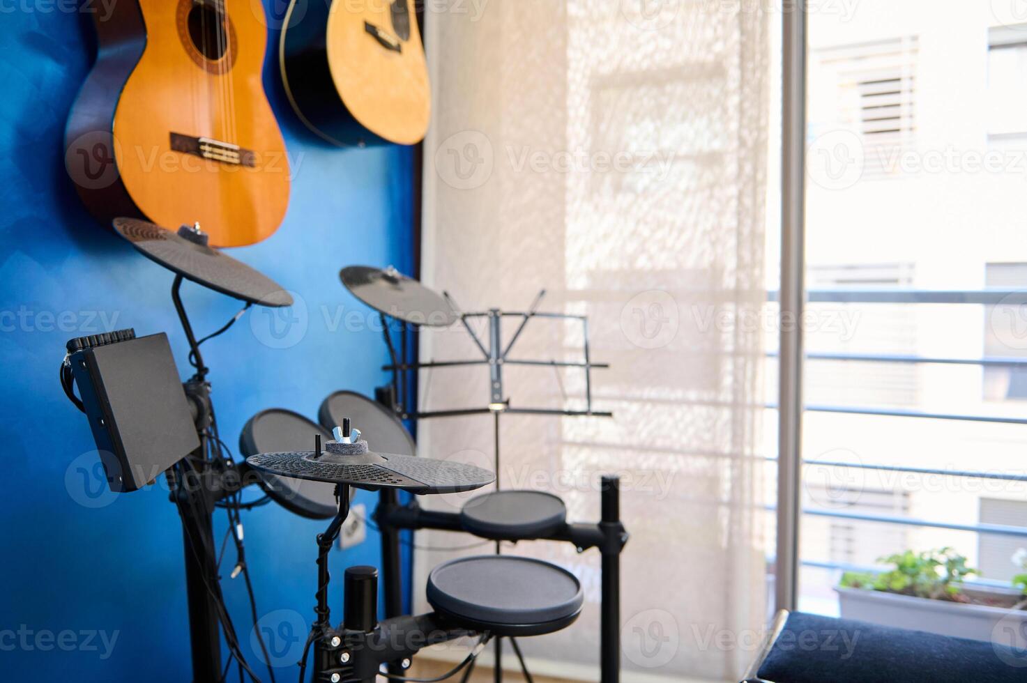 moderno interior de un música estudio para hogar usar. acústico y eléctrico guitarras colgando en azul color pared y tambor equipo con negro platillos del músico habitación para jugando y aprendizaje música. Copiar anuncio espacio foto