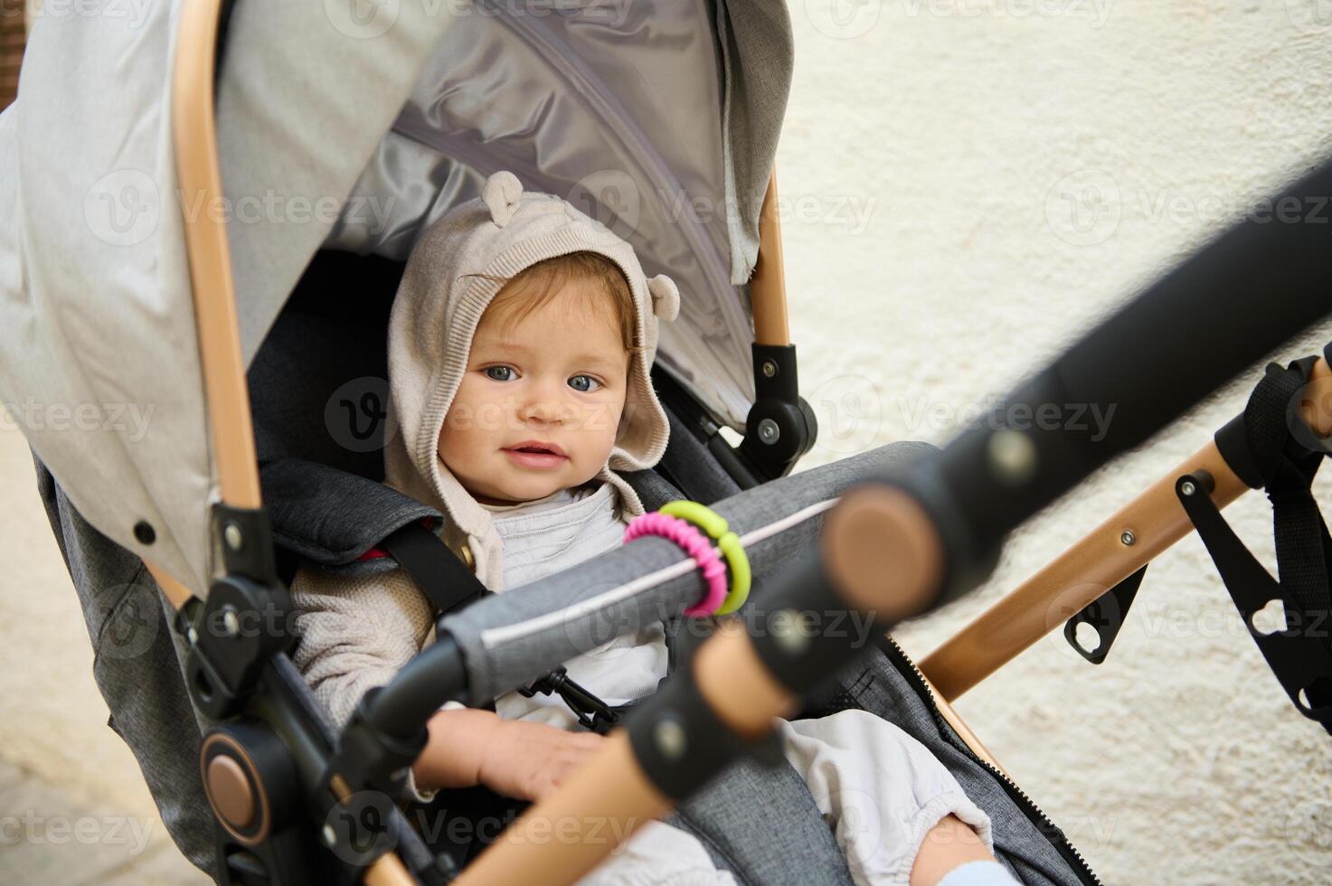 hermosa azul ojos bebé chico 6-11 meses viejo, sonriente a cámara, sentado en su bebé cochecito paseante carro cochecito foto