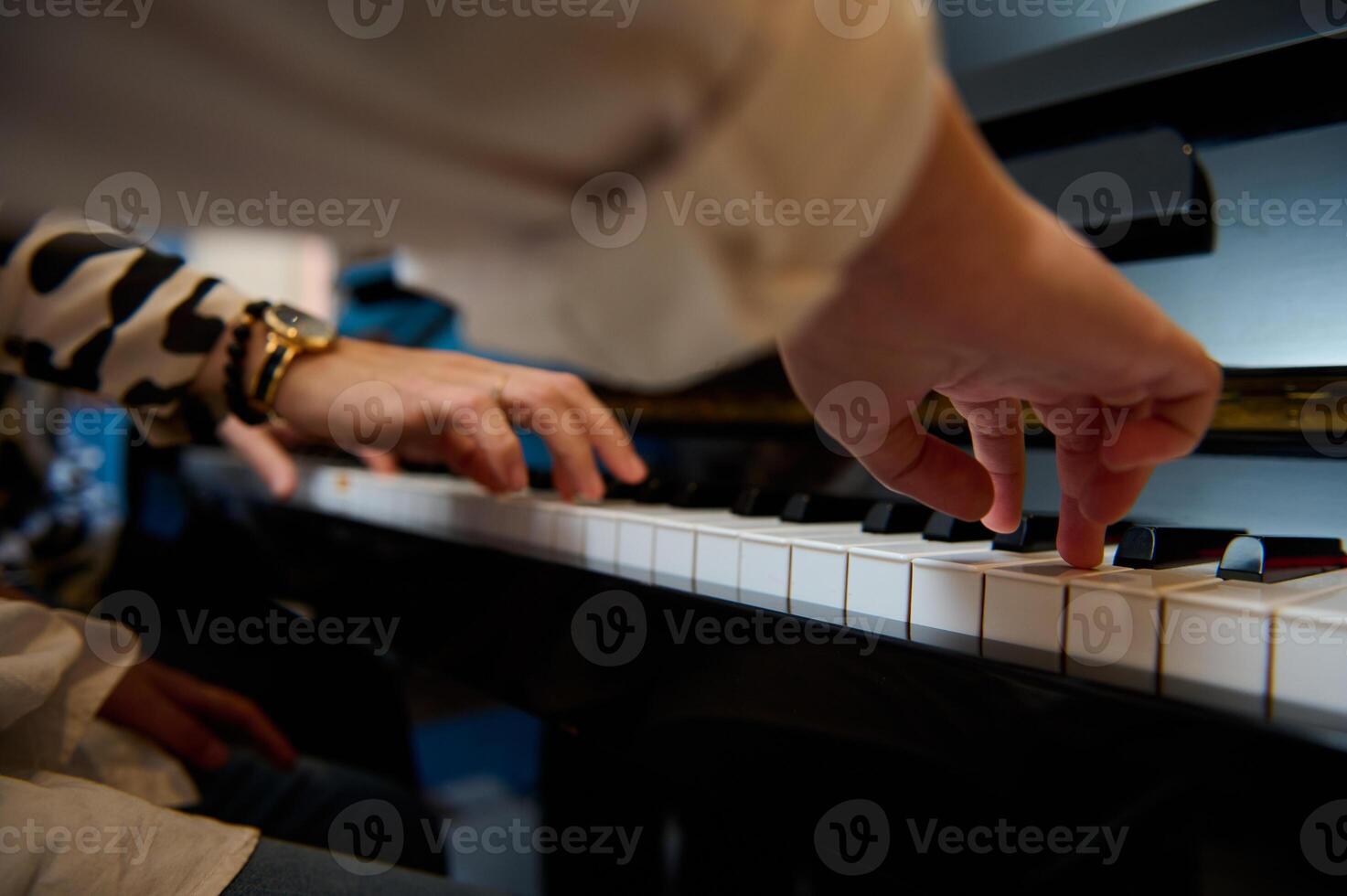 Musician boy playing grand piano during music lesson, performing classical melody, creating and feeling the rhythm of sounds while putting fingers on white and black piano keys. Close-up bottom view. photo