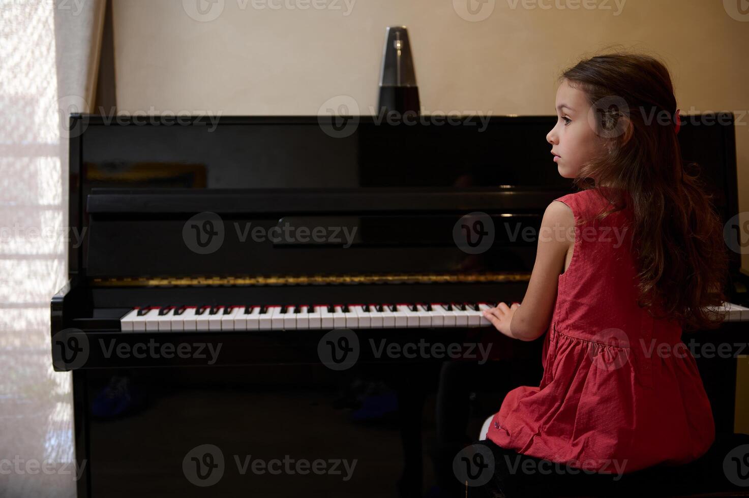 confidente retrato de un inspirado hermosa talentoso pequeño niño niña aprendizaje música, ejecutando el ritmo de clásico música mientras jugando piano, poniendo dedos en llaves y soñando mirando lejos foto