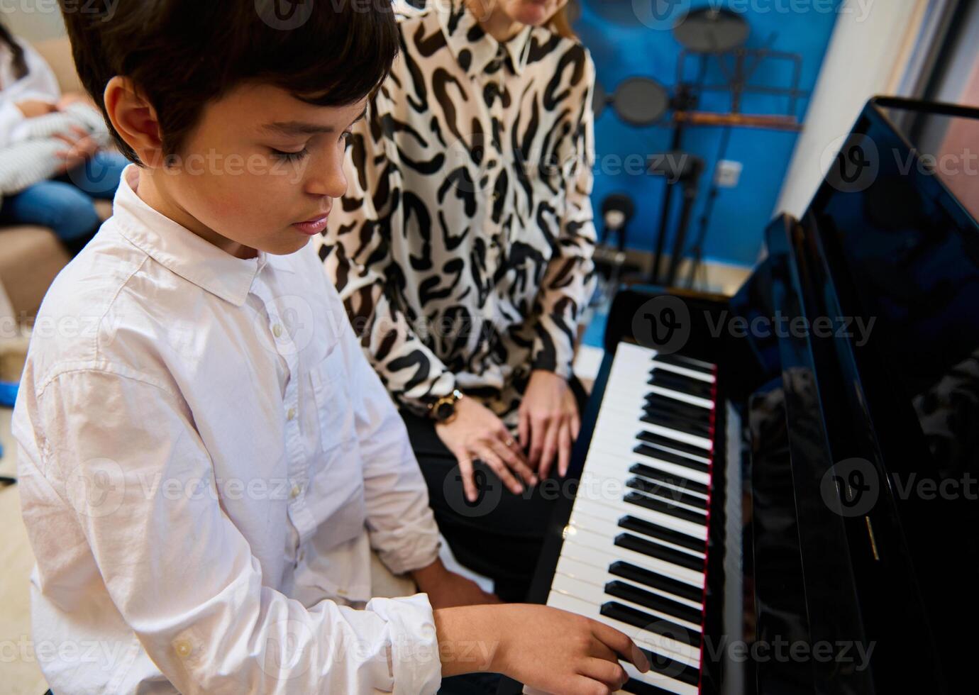 Confident talented teenage musician plays piano forte, creates music and song composes a melody during music lesson photo