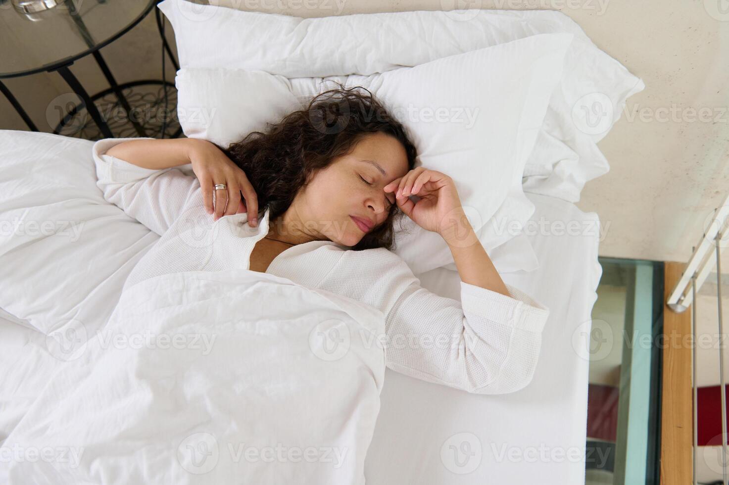 Relxed woman napping, covered with white comfortable duver photo