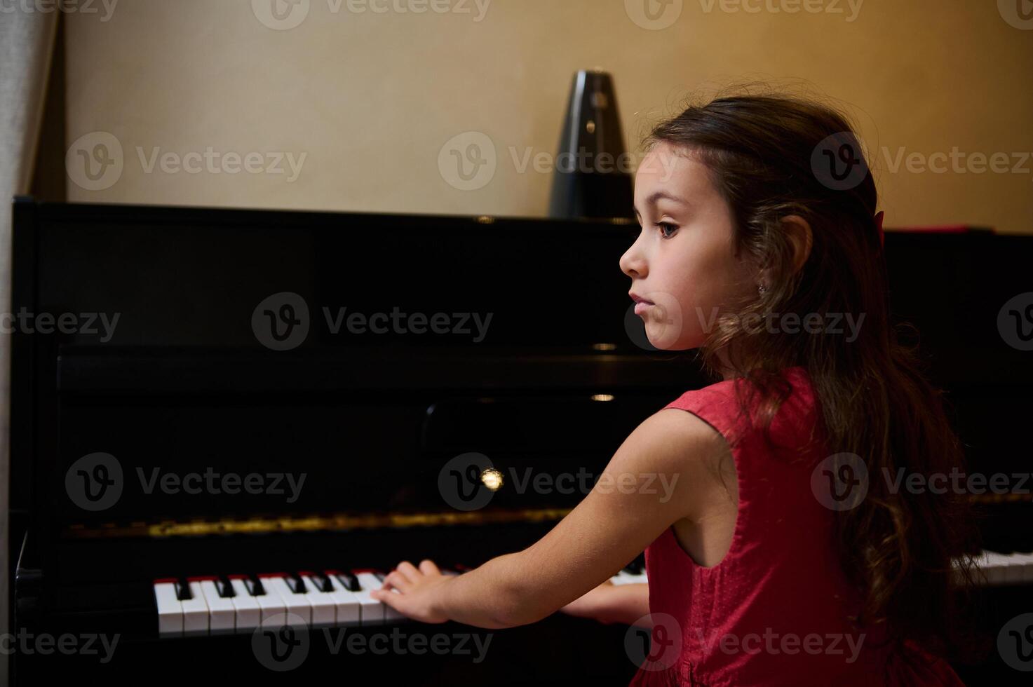 Little pianist musician girl playing piano and singing song, creating music, performing and composing melody on the pianoforte. Schoolgirl is practicing on chord instrument photo