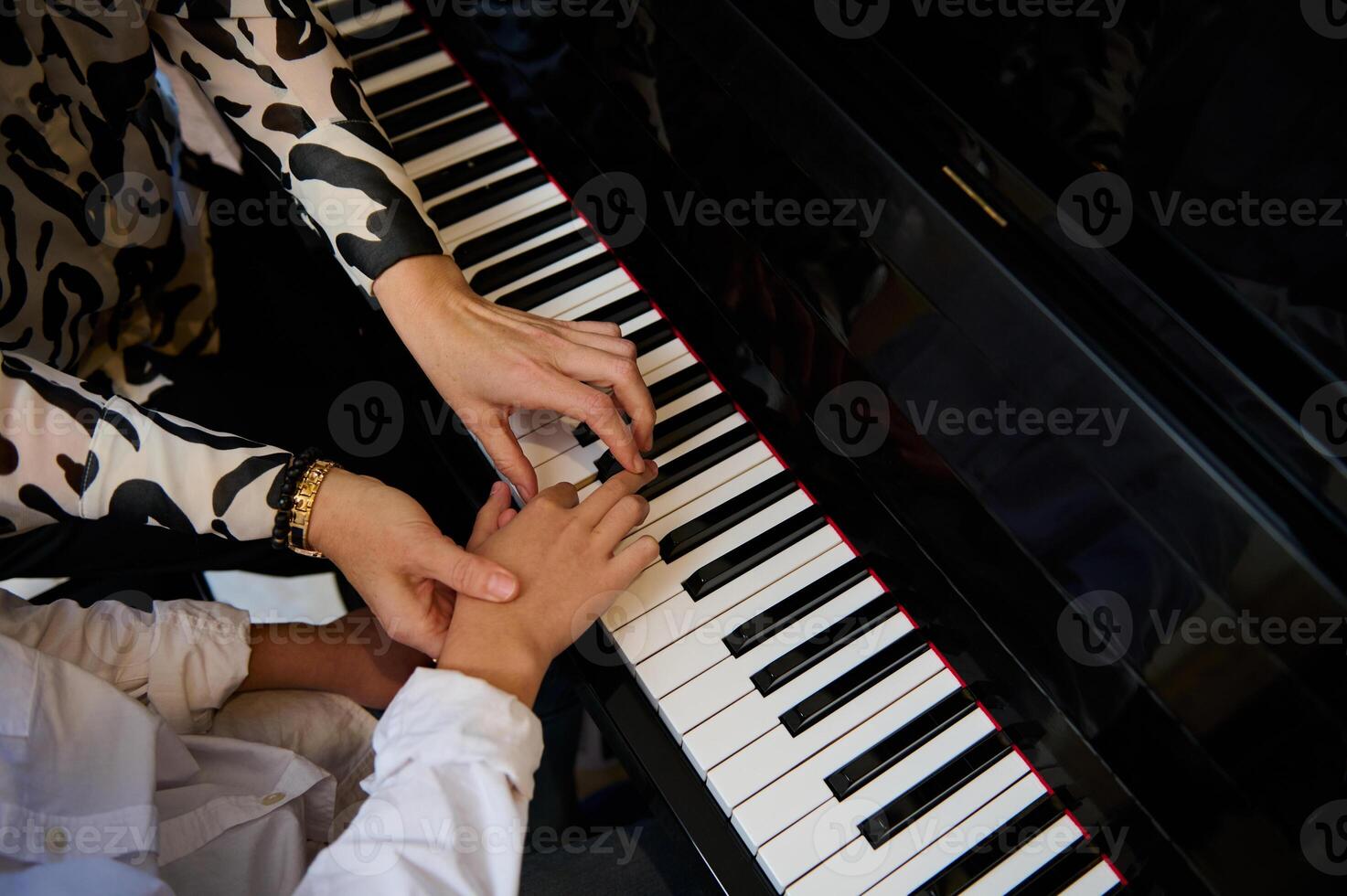 Top view hands of musician pianist teacher maestro teaching a child boy the true position of fingers on piano keys while performing musical composition on grand pianoforte, during music piano lesson photo