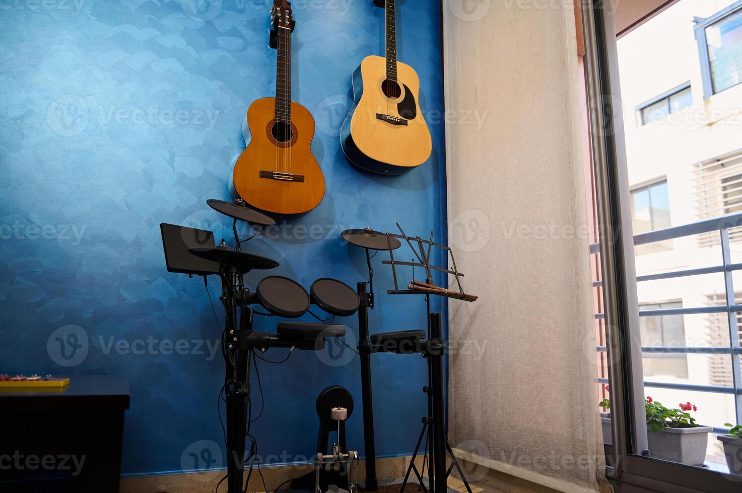 Modern interior of a music studio at home. Acoustic and electric guitars hanging on blue color wall and drum set. Hobbies and leisure. Musician's room for playing and learning music photo